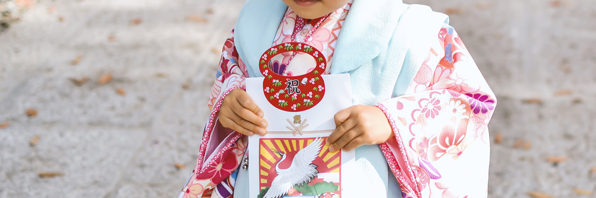 七五三で千歳飴をもってたたずむ子ども